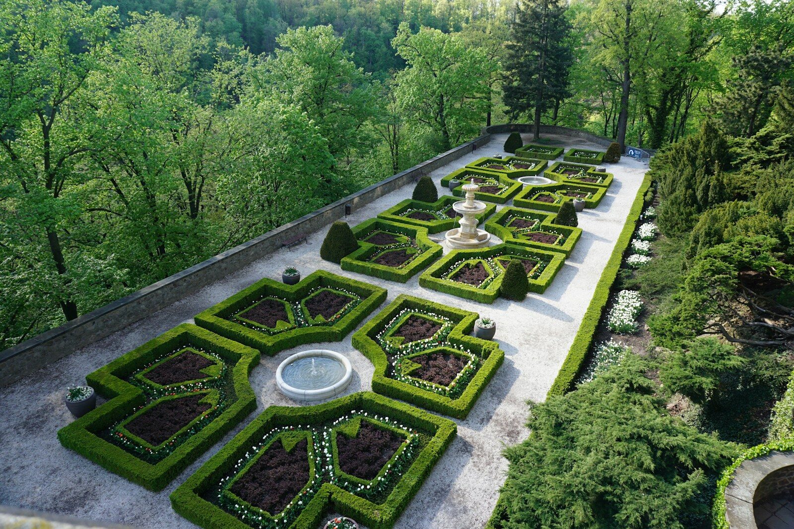 Formal french garden with manicured hedges and fountains.