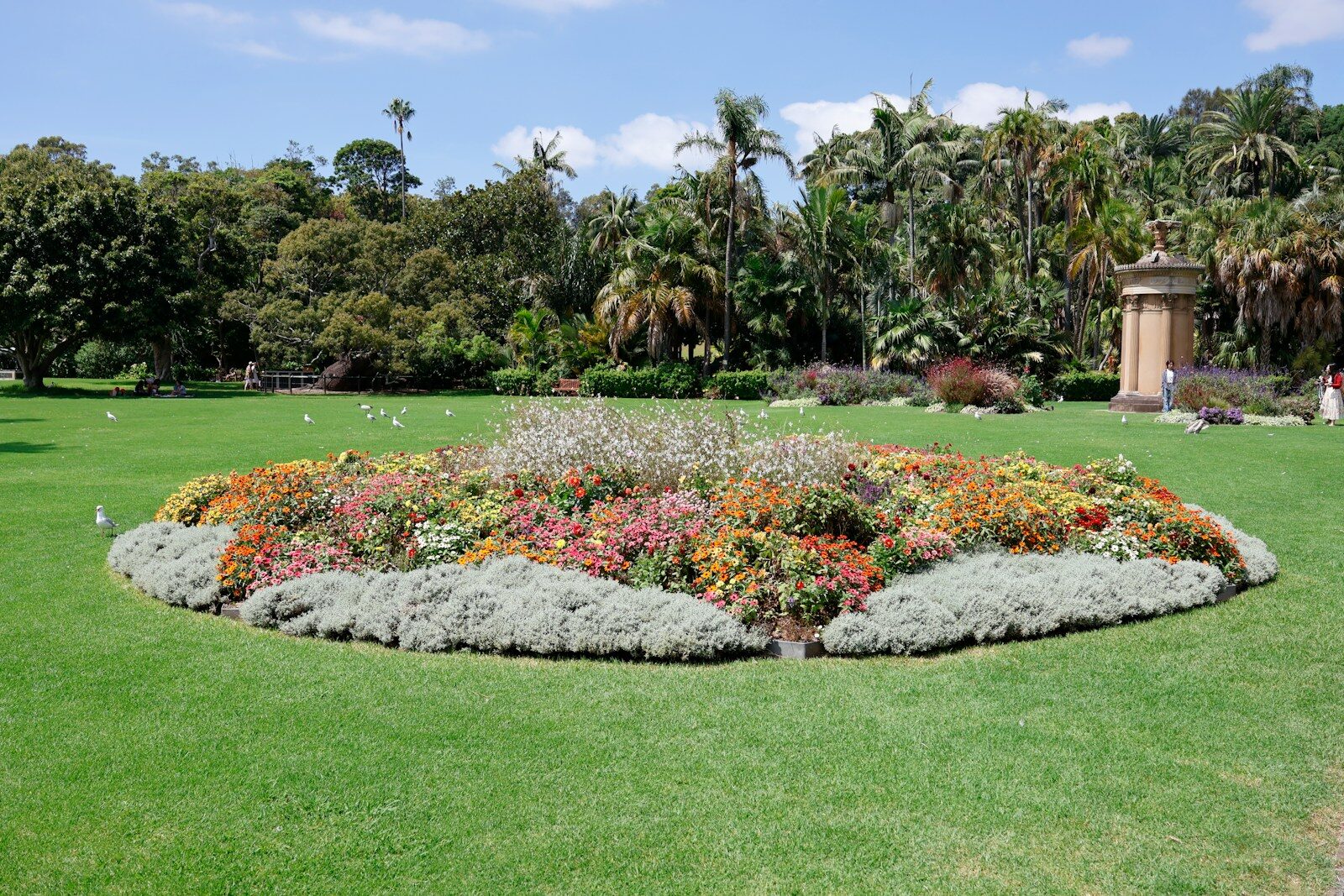 Oval flower bed with colorful blossoms in a lush park